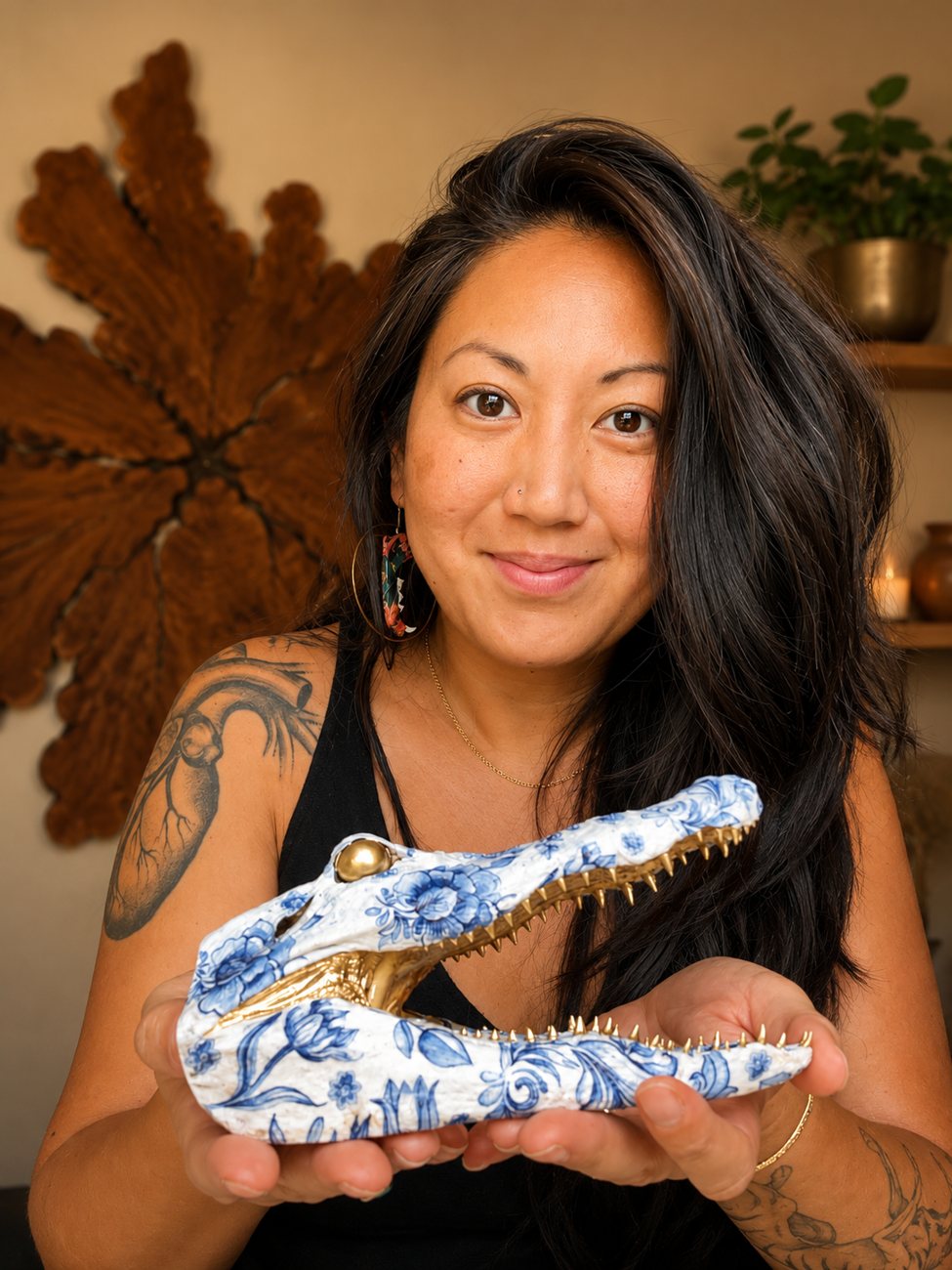 Lan smiling and holding a blue and white decorated alligator head in both hands